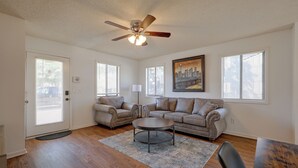 A spacious living room with hardwood flooring, a ceiling fan, a beige sofa set, a coffee table, and a painting on the wall. - Walk to Med Center! Extended Wilmington Condo (Wilmington)