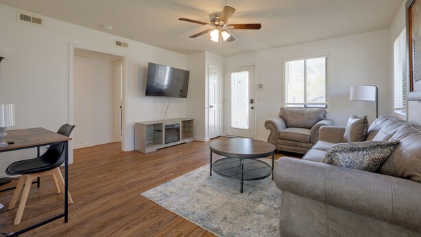 A living room with a ceiling fan, a flat-screen TV, a sofa, a coffee table, and a dining area with a table and chairs. - Walk to Med Center! Extended Wilmington Condo (Wilmington)