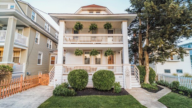 A two-story building with a balcony, potted plants, and a well-maintained lawn. - Modern Ocean City 2-unit Home Near Dtwn & Beach! (Ocean City)