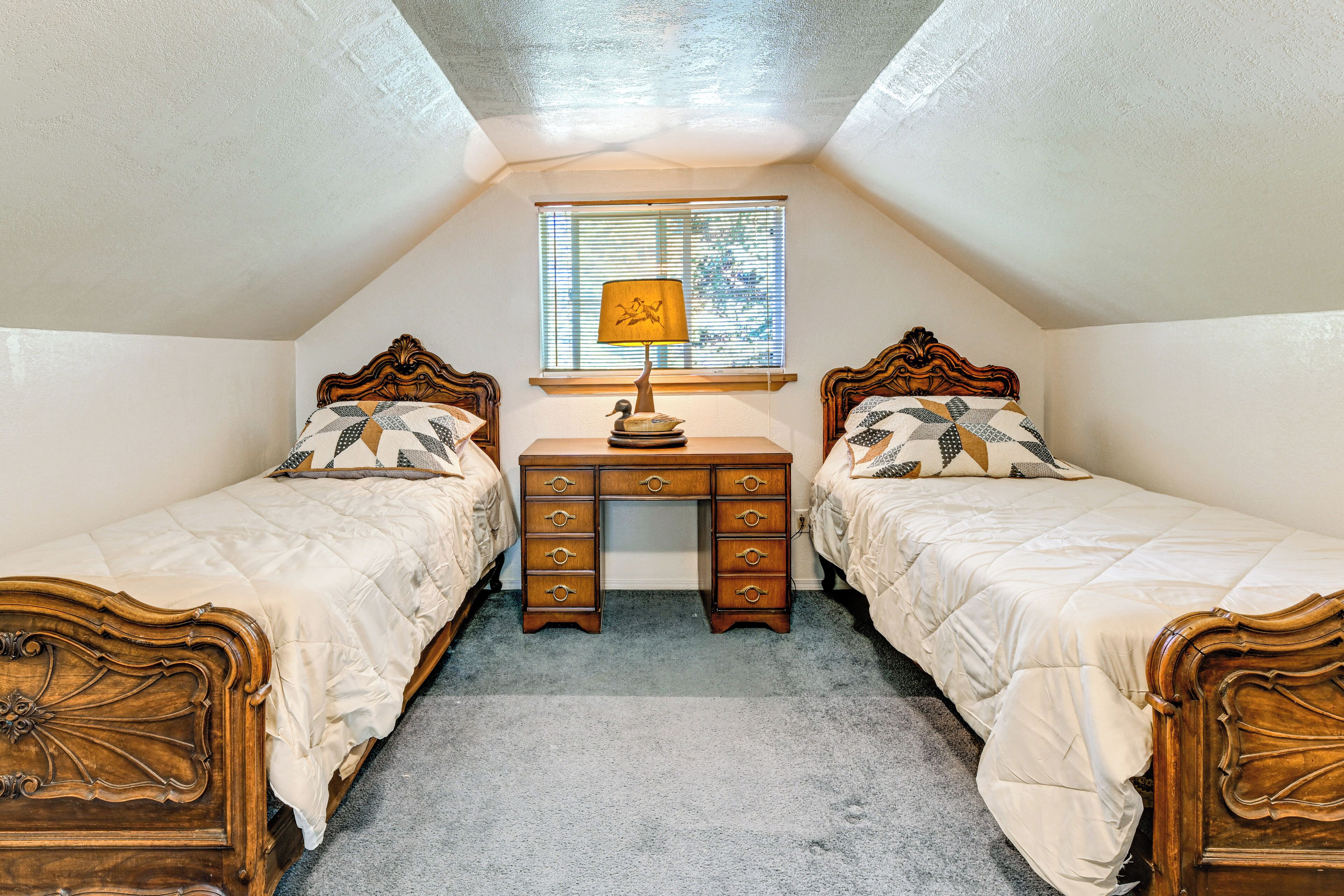 A bedroom with two wooden beds, a desk, and a window with blinds.