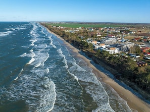 A coastal town with a beach, houses, and a large body of water. - Navango - Beachfront, Sea View Pool & Sauna (Gąski)