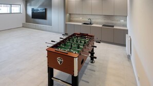 A modern kitchen with a foosball table, a TV, and built-in cabinets. - Navango - Beachfront, Sea View Pool & Sauna (Gąski)