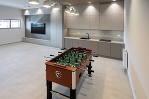 A modern kitchen with a foosball table, a TV, and built-in cabinets. - Navango - Beachfront, Sea View Pool & Sauna (Gąski)