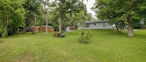 A grassy yard with a picnic table, a small shed, and a house with a covered porch.