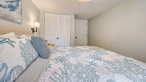 Un dormitorio con cama, mesita de noche, lámpara de pared, puerta y lámpara en el techo.