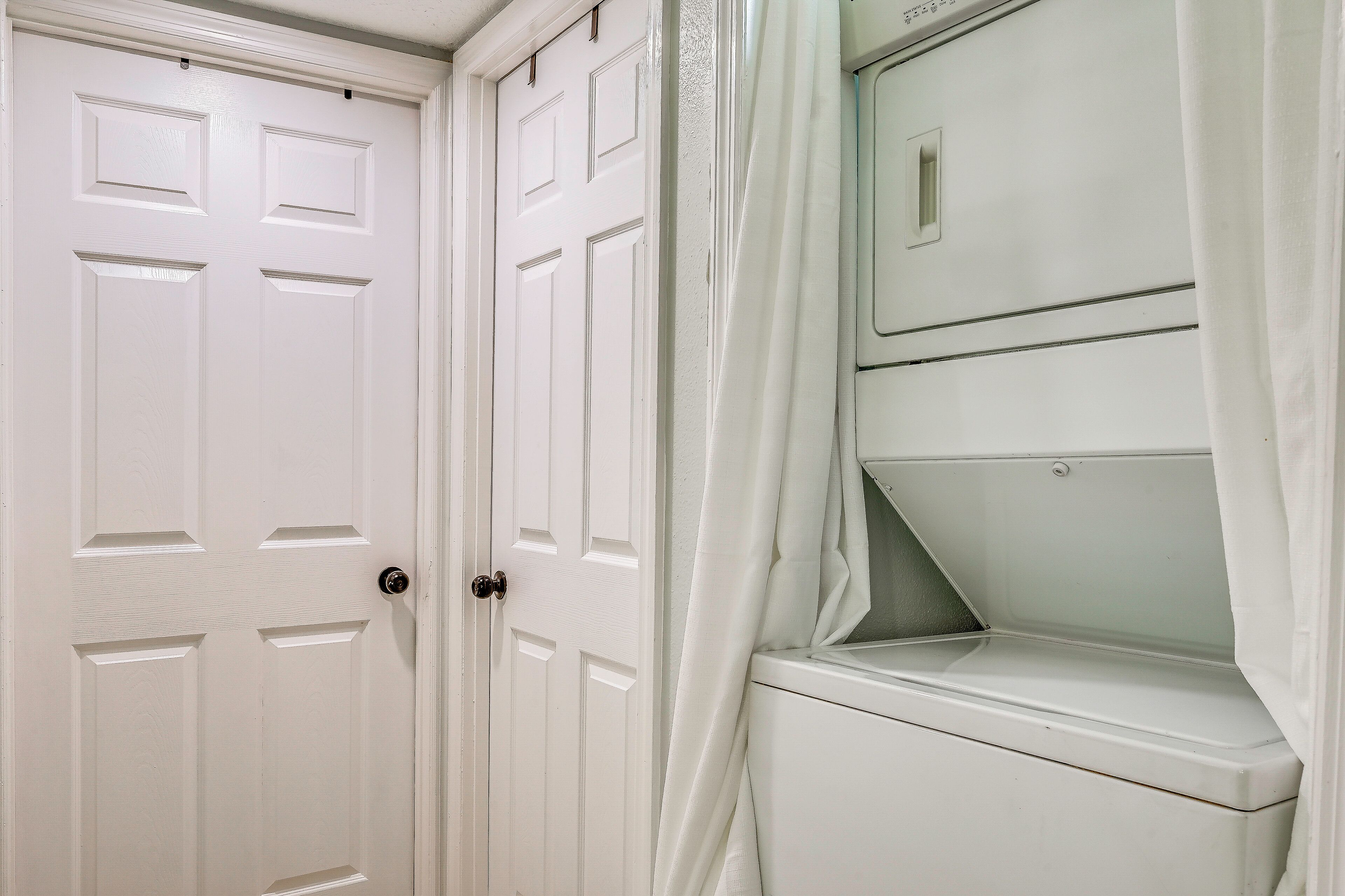 A white door with a handle and a white closet with a shelf.