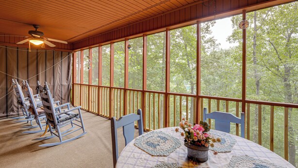 A covered porch with a table set for dining, rocking chairs, and a ceiling fan. - Charming Resort Cabin at Lake Hiwassee! (Murphy)