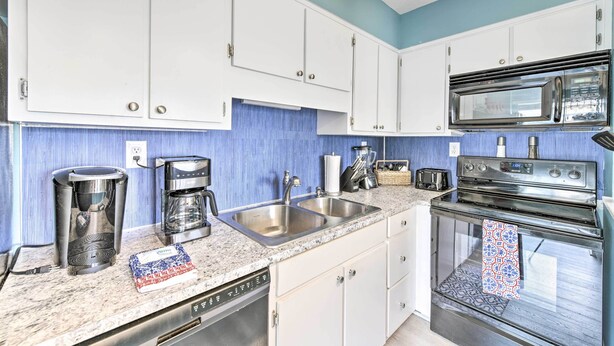 A kitchen with white cabinets, a microwave, a stove, a coffee maker, and a dishwasher. - Steps to Beach! 2-unit Combo w/ Pool Access in PCB (Panama City Beach)
