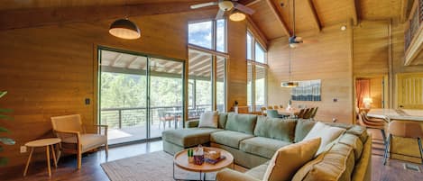 A spacious living area with a large sectional sofa, a coffee table, and a dining table with chairs. There are ceiling fans and pendant lights.