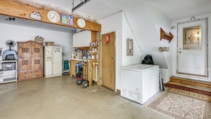 A garage with a wooden ceiling, a clock, a refrigerator, and a door with a decorative glass panel. - Game Room, Deck + Yard! Cadillac Family Escape (Cadillac)