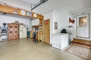 A garage with a wooden ceiling, a clock, a refrigerator, and a door with a decorative glass panel. - Game Room, Deck + Yard! Cadillac Family Escape (Cadillac)