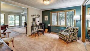 A spacious living room with a pool table, a comfortable armchair, and a dining area with a table and chairs. - Game Room, Deck + Yard! Cadillac Family Escape (Cadillac)