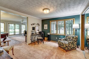 A spacious living room with a pool table, a comfortable armchair, and a dining area with a table and chairs. - Game Room, Deck + Yard! Cadillac Family Escape (Cadillac)