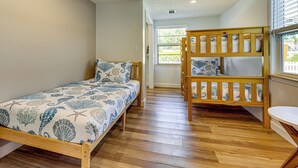 A room with a bunk bed and a single bed, both with patterned bedding. - Walk to the Sand! St Augustine Beach Bungalow (St. Augustine)