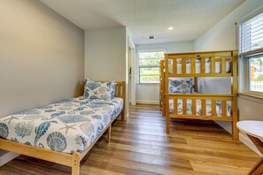 A room with a bunk bed and a single bed, both with patterned bedding. - Walk to the Sand! St Augustine Beach Bungalow (St. Augustine)