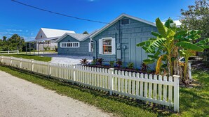 A two-story house with a white picket fence, a paved driveway, and a well-maintained lawn. - Walk to the Sand! St Augustine Beach Bungalow (St. Augustine)
