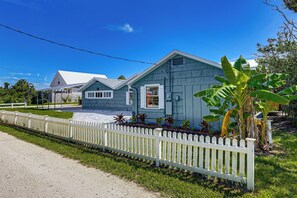 A two-story house with a white picket fence, a paved driveway, and a well-maintained lawn. - Walk to the Sand! St Augustine Beach Bungalow (St. Augustine)
