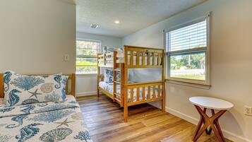 A bedroom with a bunk bed, a small round table, and a window with blinds.