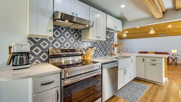A modern kitchen with white cabinets, a stainless steel range, and patterned backsplash.
