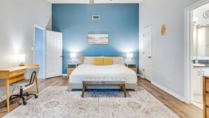 Un dormitorio con cama, mesitas de noche, escritorio y silla.