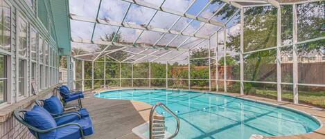 A covered swimming pool with blue chairs and a pool ladder.