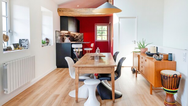 Een moderne keuken met een houten tafel, stoelen en een rode accentmuur.