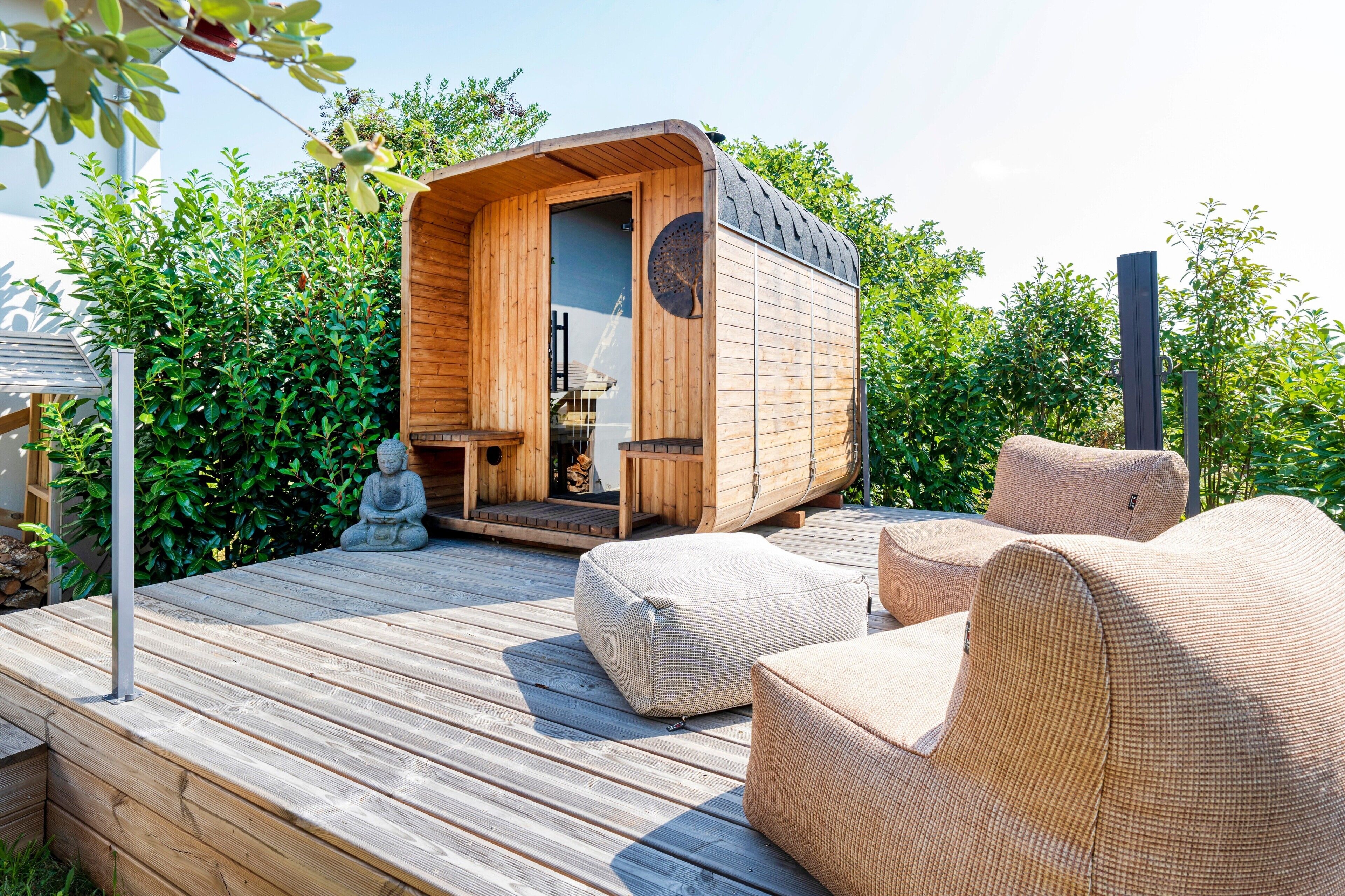A wooden cabin with a door, a small table, and two wicker chairs on a wooden deck.