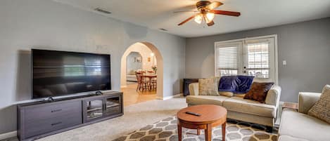 A living room with a flat-screen TV, a ceiling fan, a sofa, a coffee table, and a patterned rug.