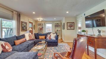 A living room with a sectional sofa, a coffee table, a patterned rug, and a wooden sideboard.