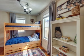 A bunk bed with a blue mattress, a wooden headboard, and a patterned rug.