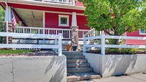 A red house with a white porch, a set of concrete steps leading to the entrance, and a tree in the foreground. - Historic Downtown Castle Rock Home (Castle Rock)