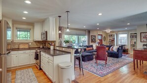 A spacious living area with a kitchen, dining space, and a large window providing natural light. - Historic Downtown Castle Rock Home (Castle Rock)