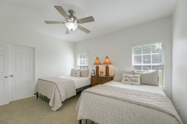 A bedroom with two beds, a ceiling fan, a nightstand with lamps, and a window with blinds. - On 174 Acres! Ranch House in Colorado County (Weimar)
