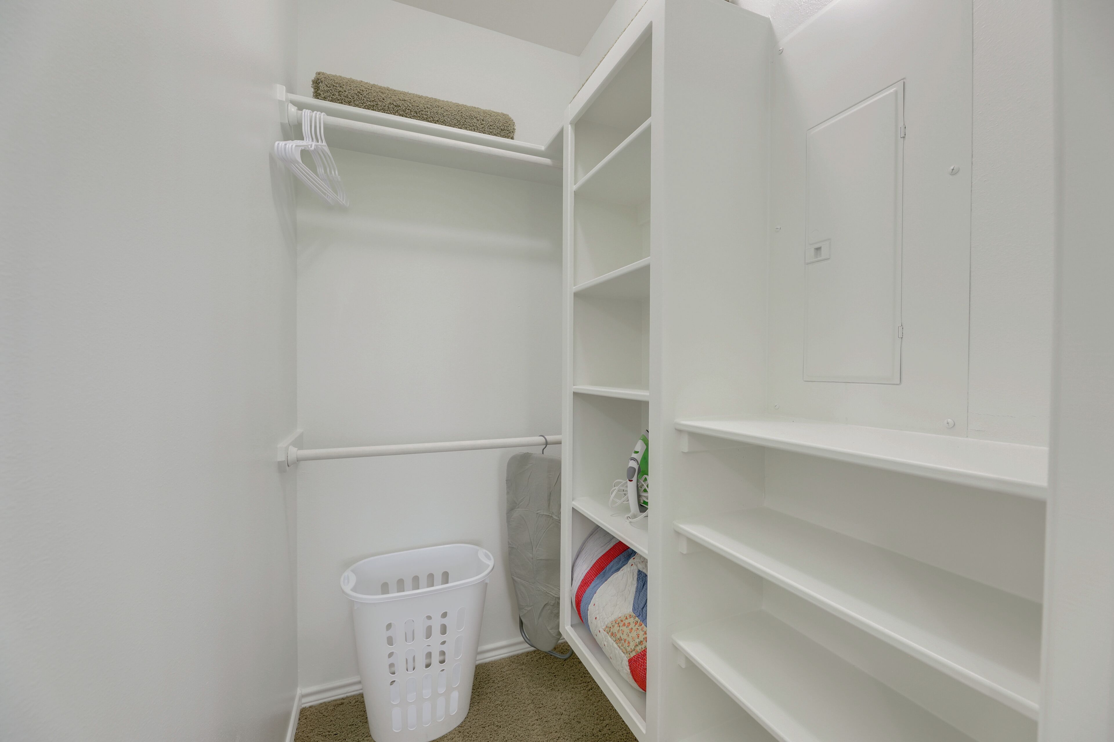 Un lavadero blanco con estantes, una cesta y un tendedero.