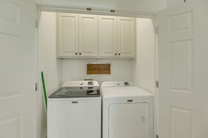 A laundry room with two Maytag washers and dryers, white cabinets above, and a 'RANCH LIFE' sign on the wall. - On 174 Acres! Ranch House in Colorado County (Weimar)