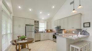 A kitchen with white cabinets, a central island, a dining table with chairs, and pendant lighting. - On 174 Acres! Ranch House in Colorado County (Weimar)