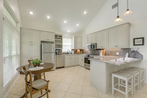 A kitchen with white cabinets, a central island, a dining table with chairs, and pendant lighting. - On 174 Acres! Ranch House in Colorado County (Weimar)