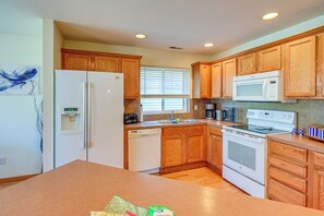 A kitchen with wooden cabinets, a refrigerator, a microwave, a dishwasher, and a stove.