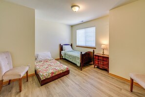 Ein Schlafzimmer mit zwei Betten, einem Sessel, einem Nachttisch und einer Lampe.