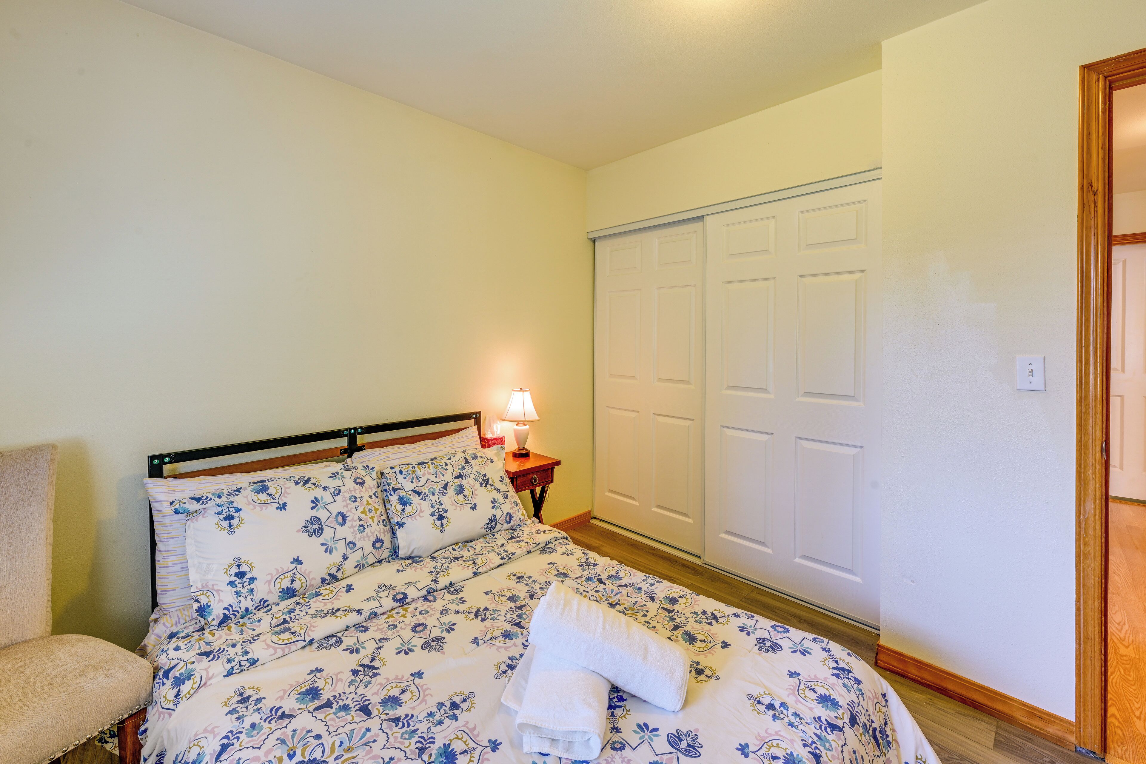 A bedroom with a bed, a nightstand, a lamp, and a wardrobe.