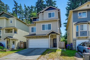 A two-story residential building with a garage, a front porch, and a driveway.