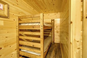Habitación con literas de madera y un cartel en la pared.