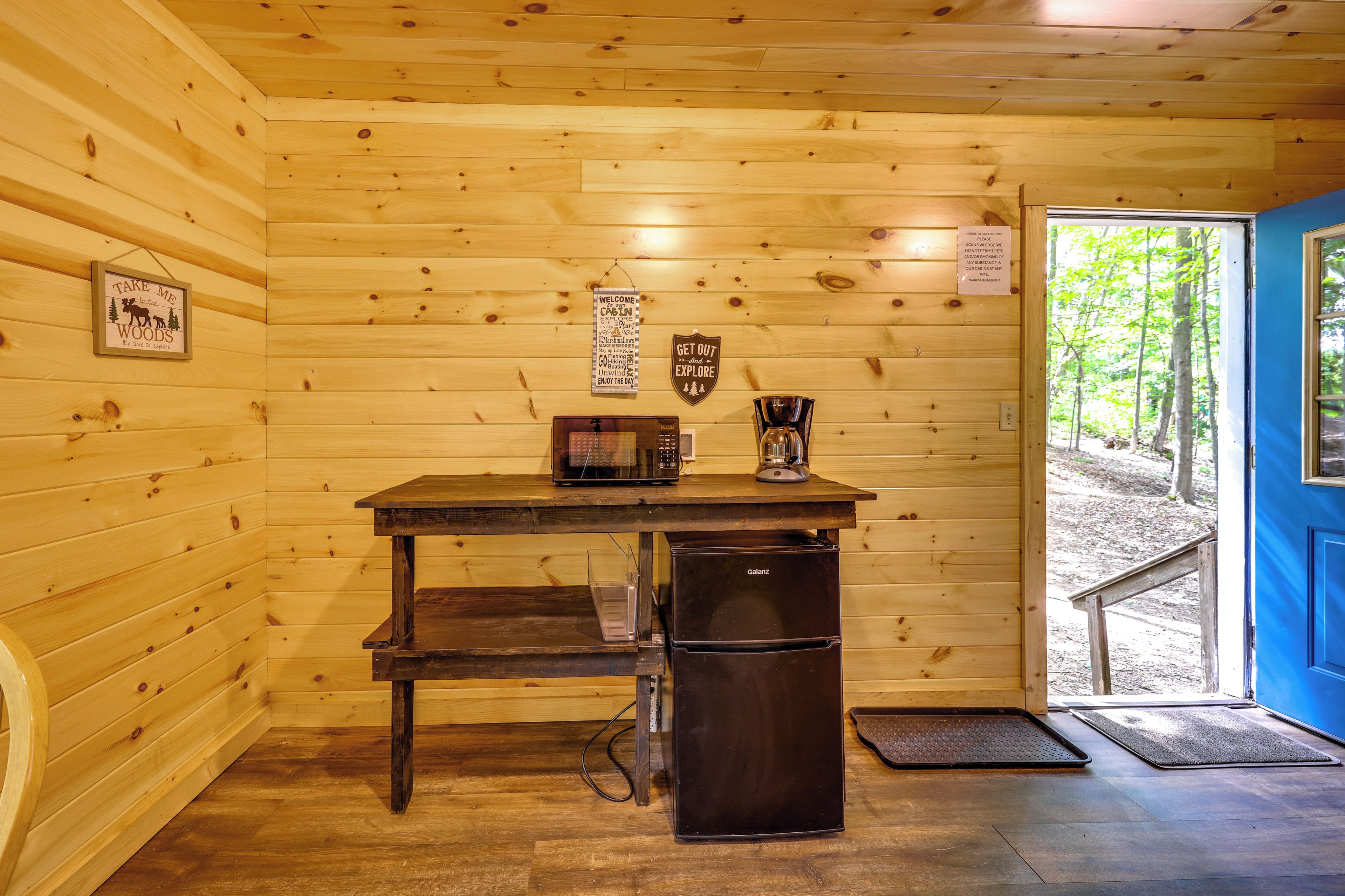 A wooden cabin interior with a table, a refrigerator, and a coffee maker.