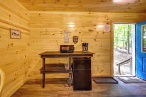 A wooden cabin interior with a table, a refrigerator, and a coffee maker.