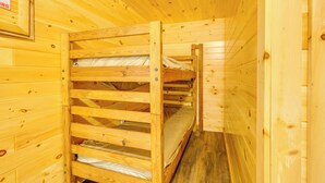 Interno di una baita in legno con letti a castello e una targa appesa al muro.