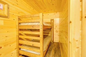 A wooden cabin interior with bunk beds and a framed sign on the wall.