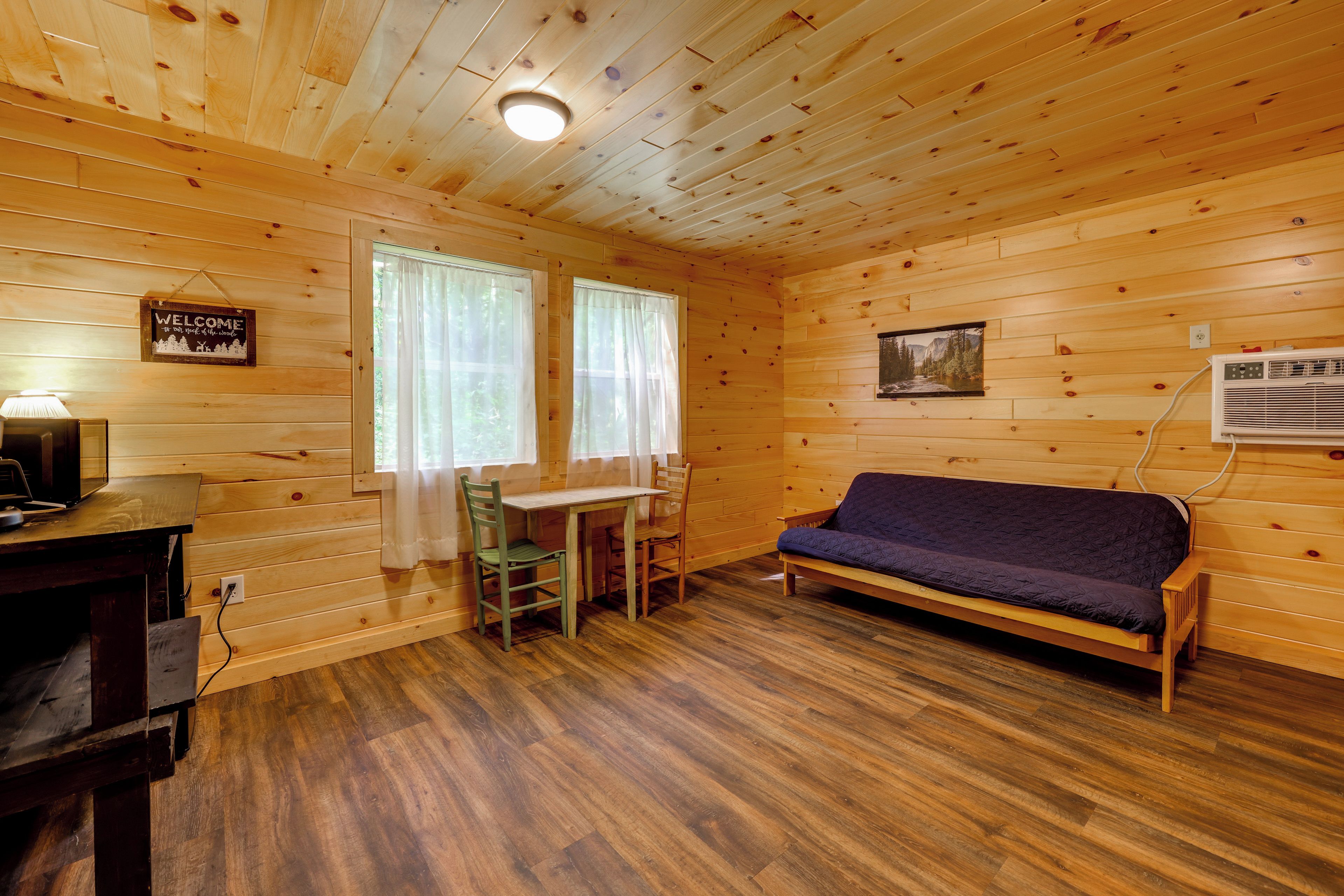 A wooden cabin interior with a sofa, a table, and a chair.
