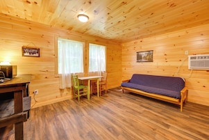 Interior de una cabaña de madera con sofá, una mesa y sillas.