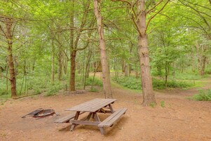 Una mesa de picnic en un bosque, con un pozo de fuego cerca.