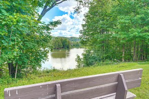 A wooden bench overlooking a lake surrounded by dense greenery.